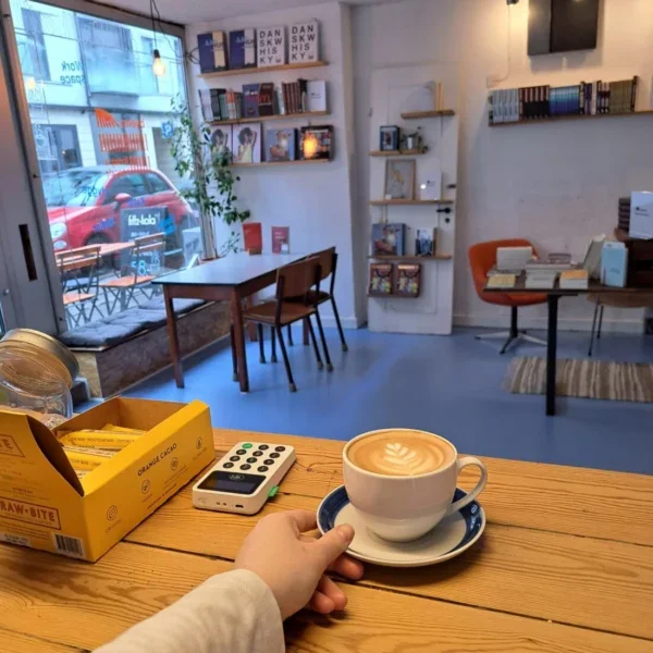 En kop kaffe med latte-art på et bord på Byens Forlags hyggelige bogcafé i Aarhus.