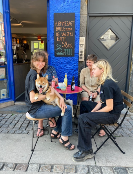 Tre personer og en hund sidder ved et bord uden for bogcafe i København.